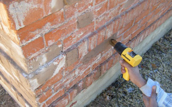 A person using a drill to fix the wall.