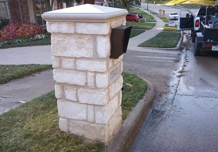 A brick mailbox on the side of a street.